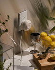 Retractable USB-C wall charger plugged in above a kitchen counter with lemons, a citrus juicer and a silver goblet