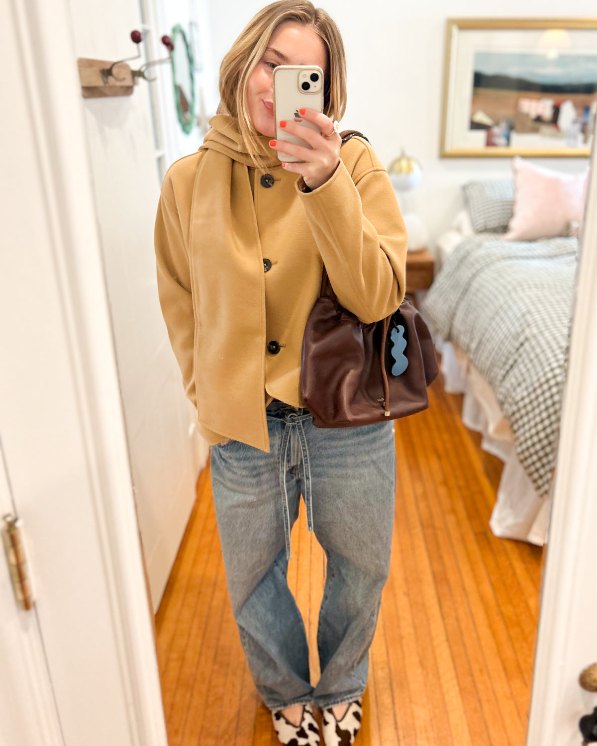 Woman wearing Dyad chocolate brown leather bag crossbody with jeans and tan jacket.