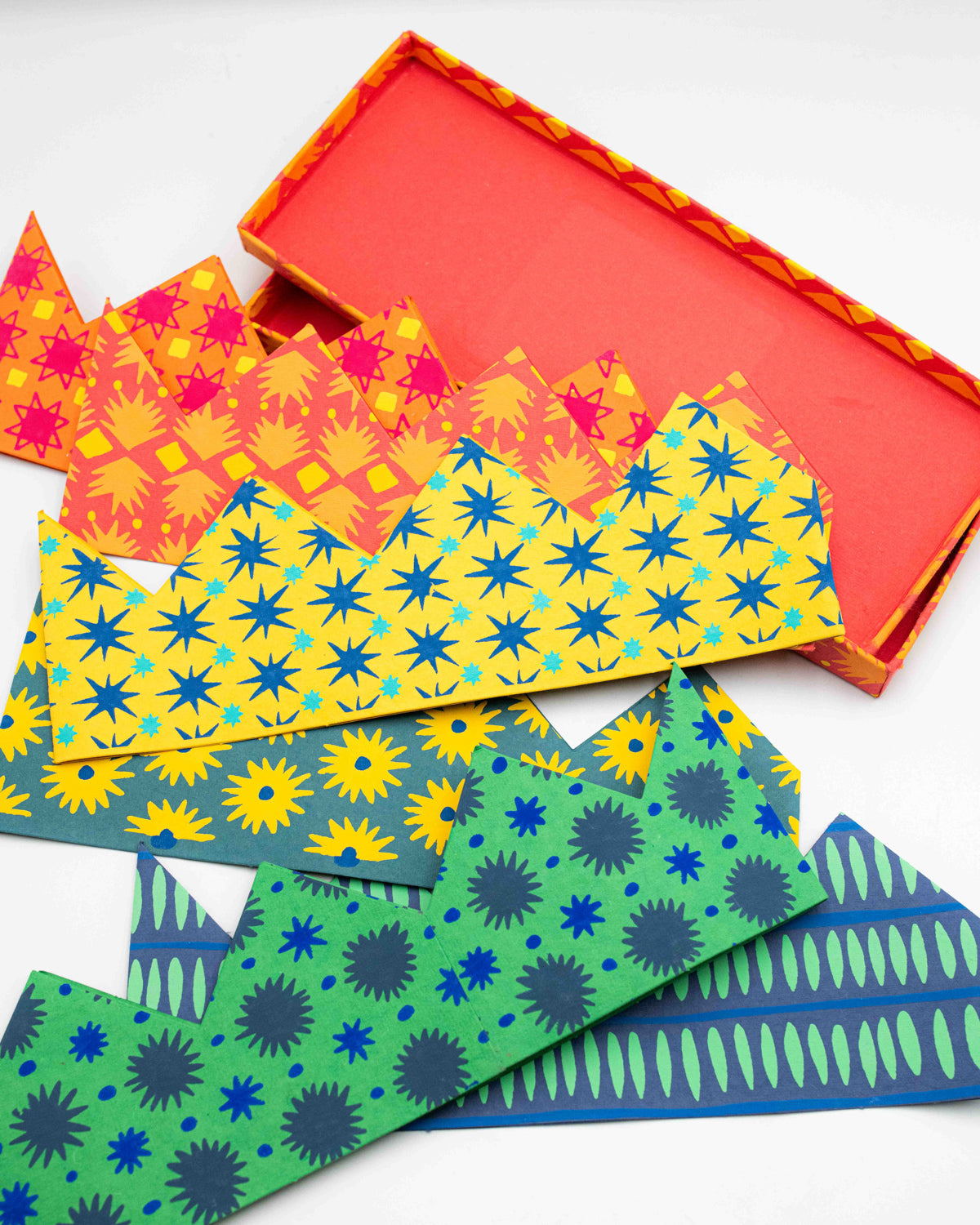 East End Press celebration crowns in orange, yellow, green and blue prints spilling from their box