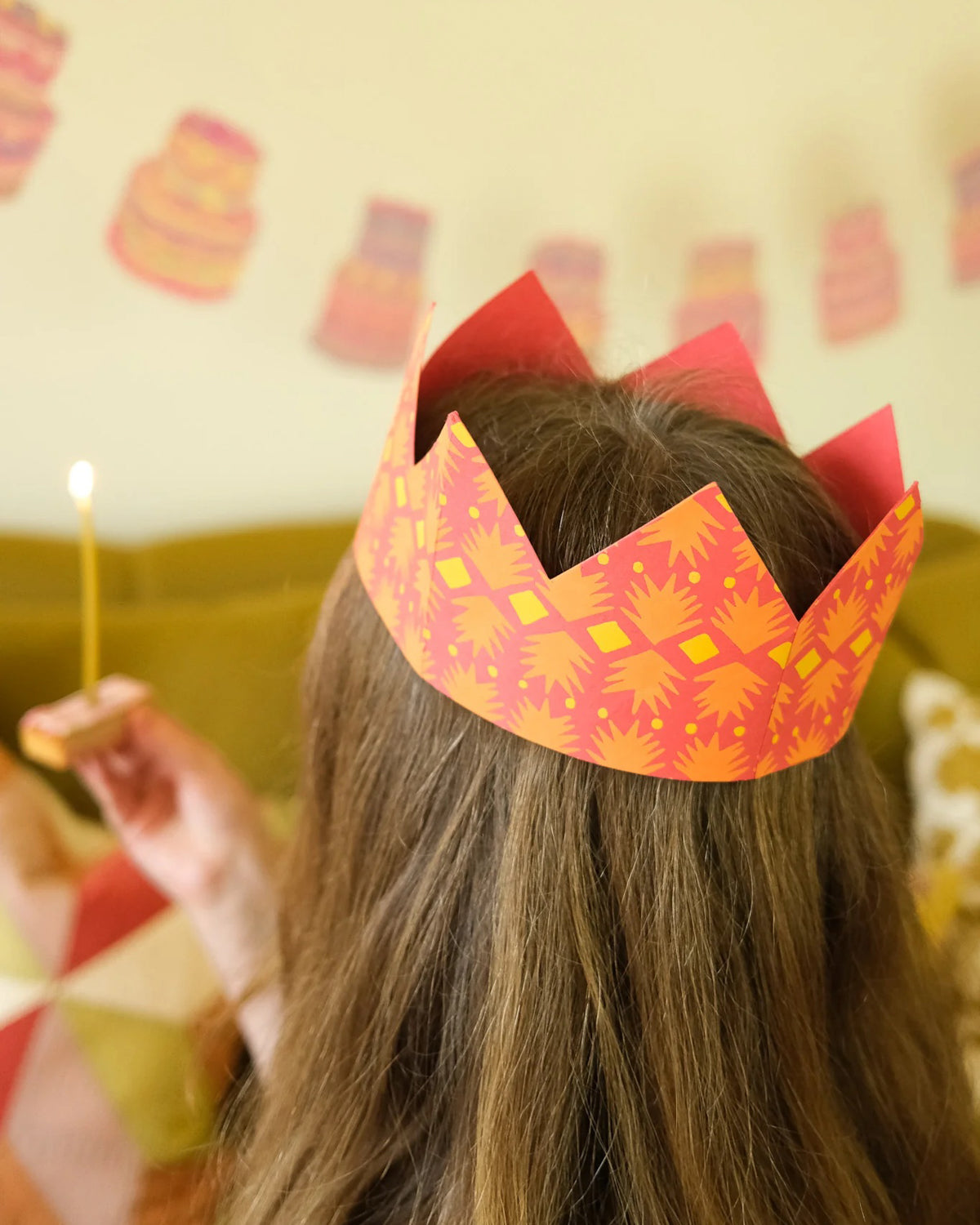 Child wearing an orange patterned paper crown at a birthday party