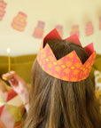 Child wearing an orange patterned paper crown at a birthday party