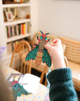 Child hanging a teal and gold paper moth from the insect garland in a sunny living room
