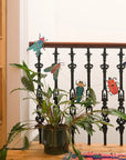 Paper insect garland draped along a black iron stair railing above a potted plant