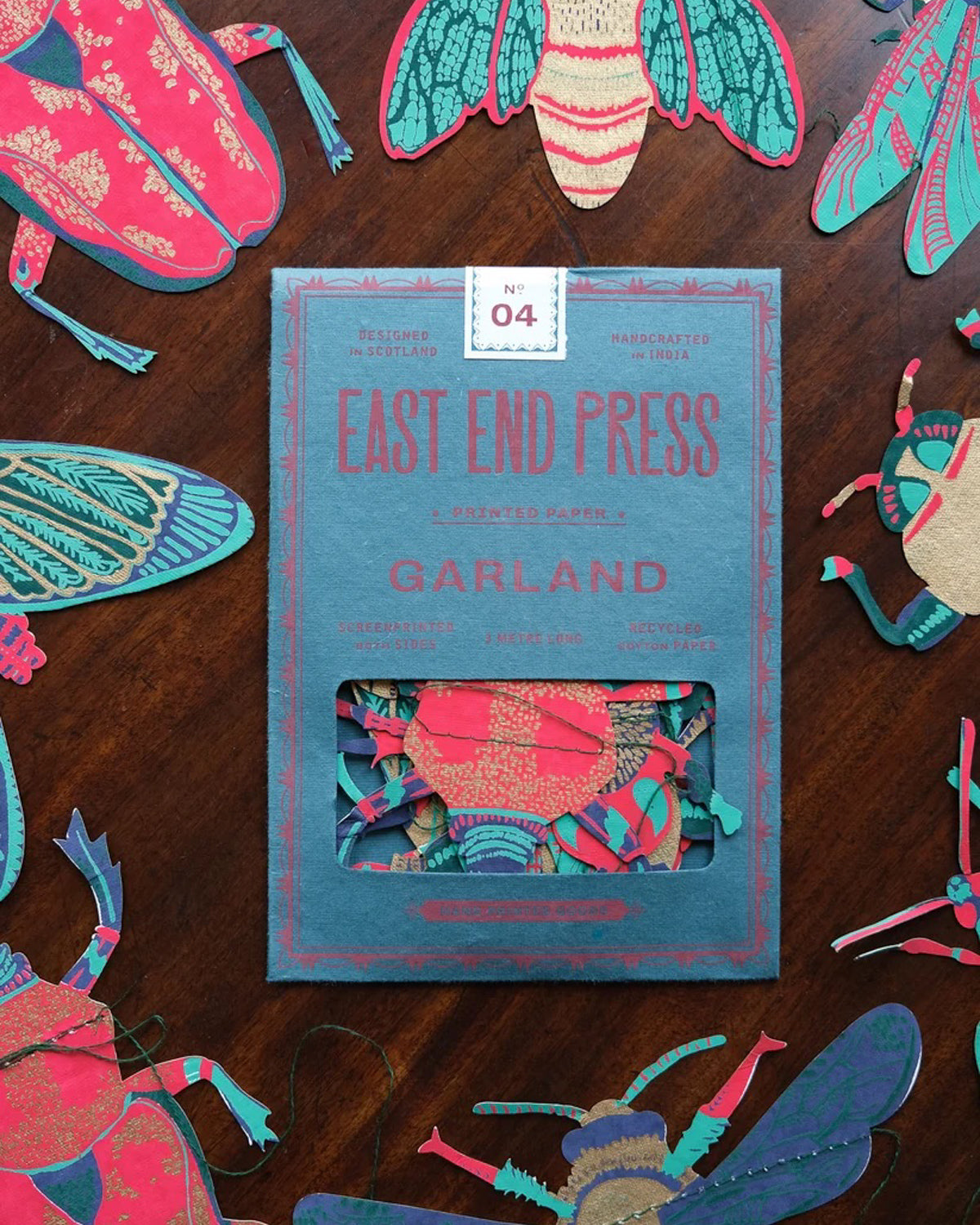 East End Press insect garland in its teal packet, surrounded by paper beetles and moths