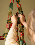 Hands linking hand-printed red and green paper chain strips