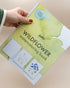 Hand holding the spiral-bound Wildflower watercoloring book by Elizabeth Wade