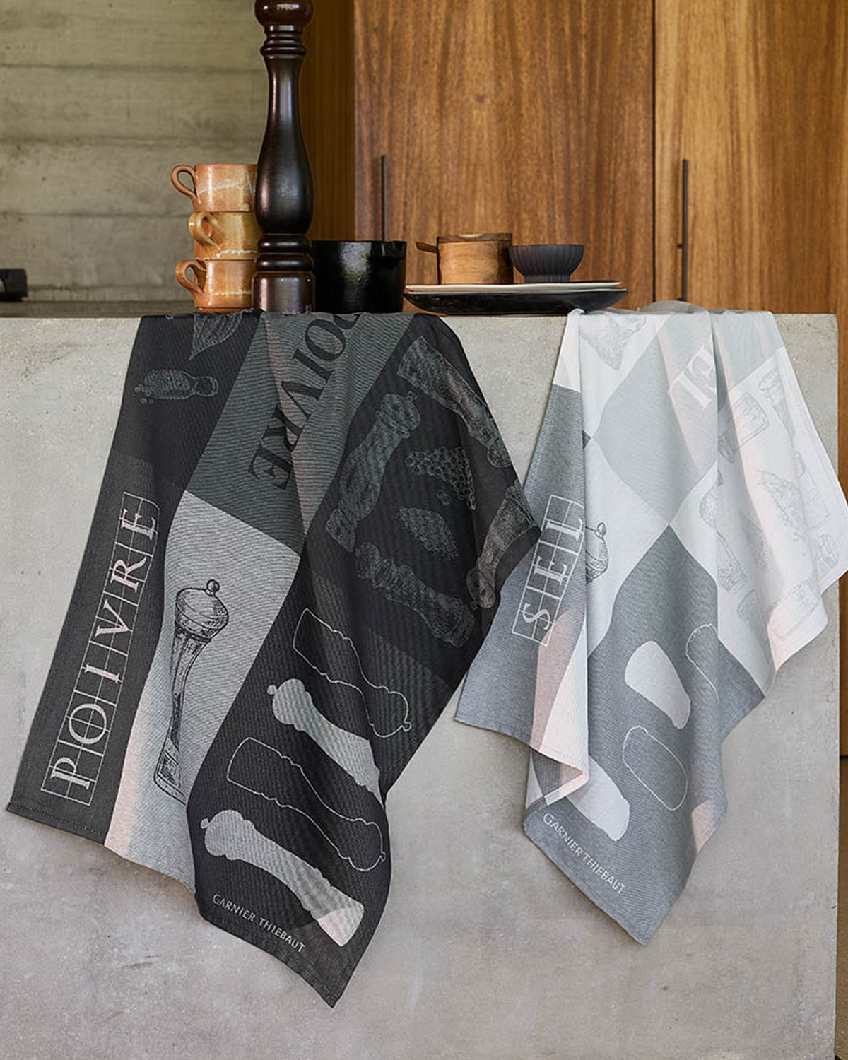 Poivre and Sel jacquard kitchen towels in charcoal and gray hanging over a kitchen counter