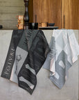 Poivre and Sel jacquard kitchen towels in charcoal and gray hanging over a kitchen counter