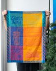 Person holding up the Street Food jacquard kitchen towel with burger, soda and fries graphics in teal and orange