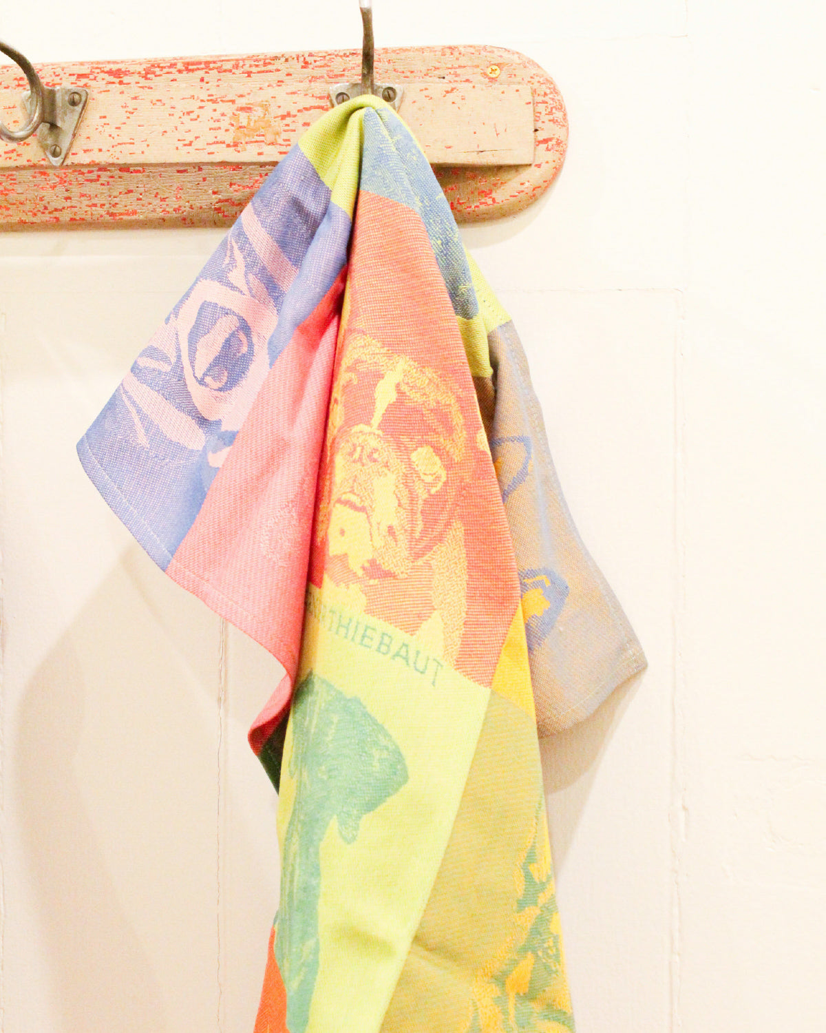 Pop art jacquard kitchen towels hanging from a wooden wall hook, with the dog design in front