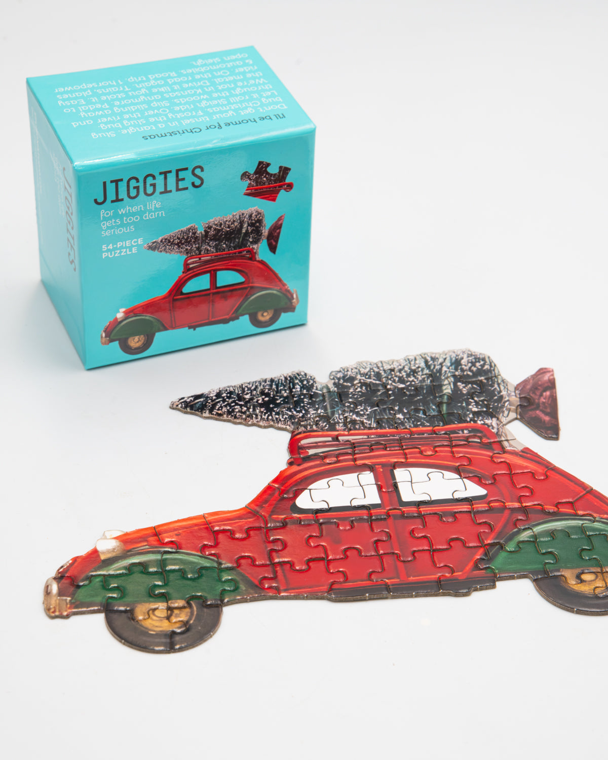 Jiggies mini puzzle of a red car with a Christmas tree on top, beside its teal box