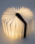 Folding book light opened almost all the way around, with dark wood covers
