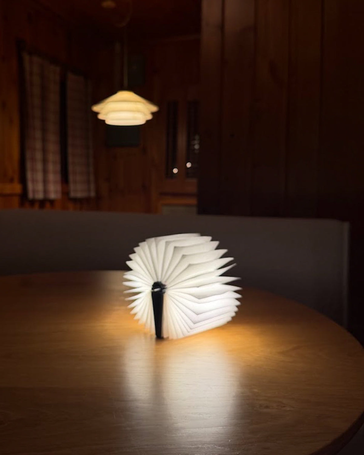 Glowing origami book light on a round table in a dim cabin room