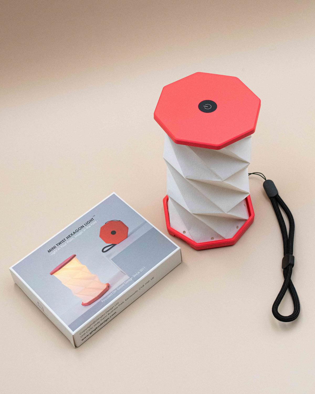 Hexagon twist light with coral top and base popped open beside its box and wrist strap
