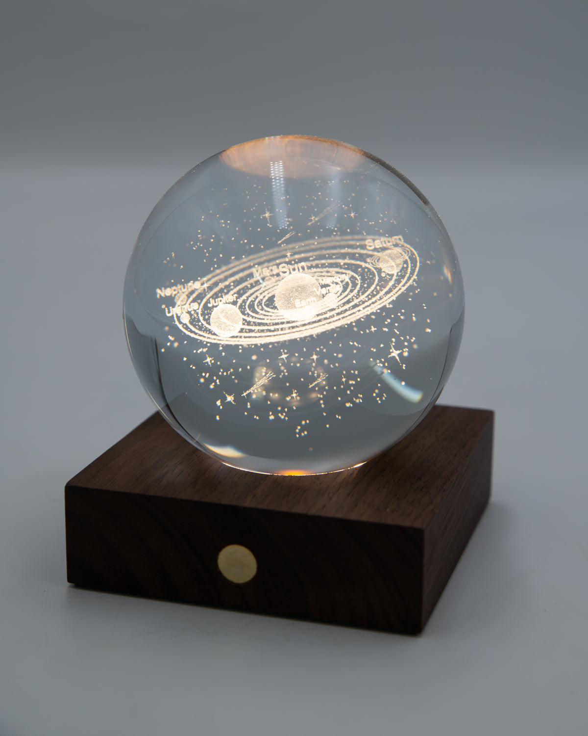 Crystal ball with the solar system engraved inside, lit on a walnut base