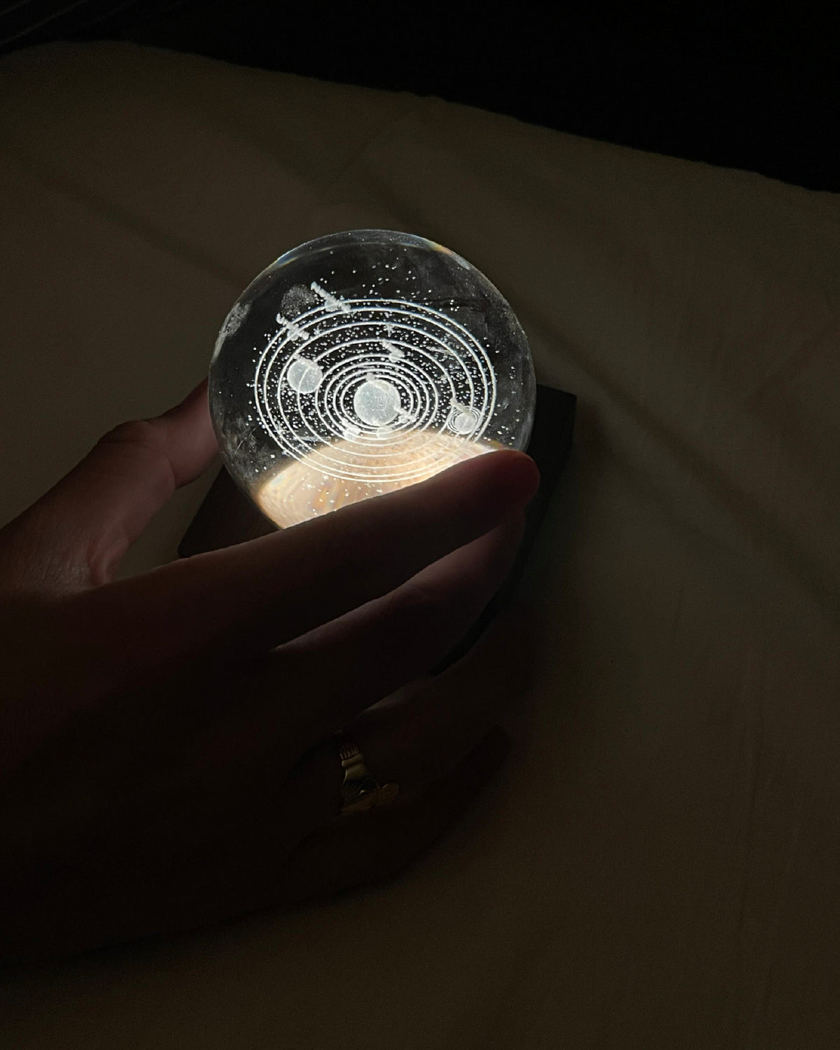 Hand holding the planetary system crystal ball light glowing in a dark room