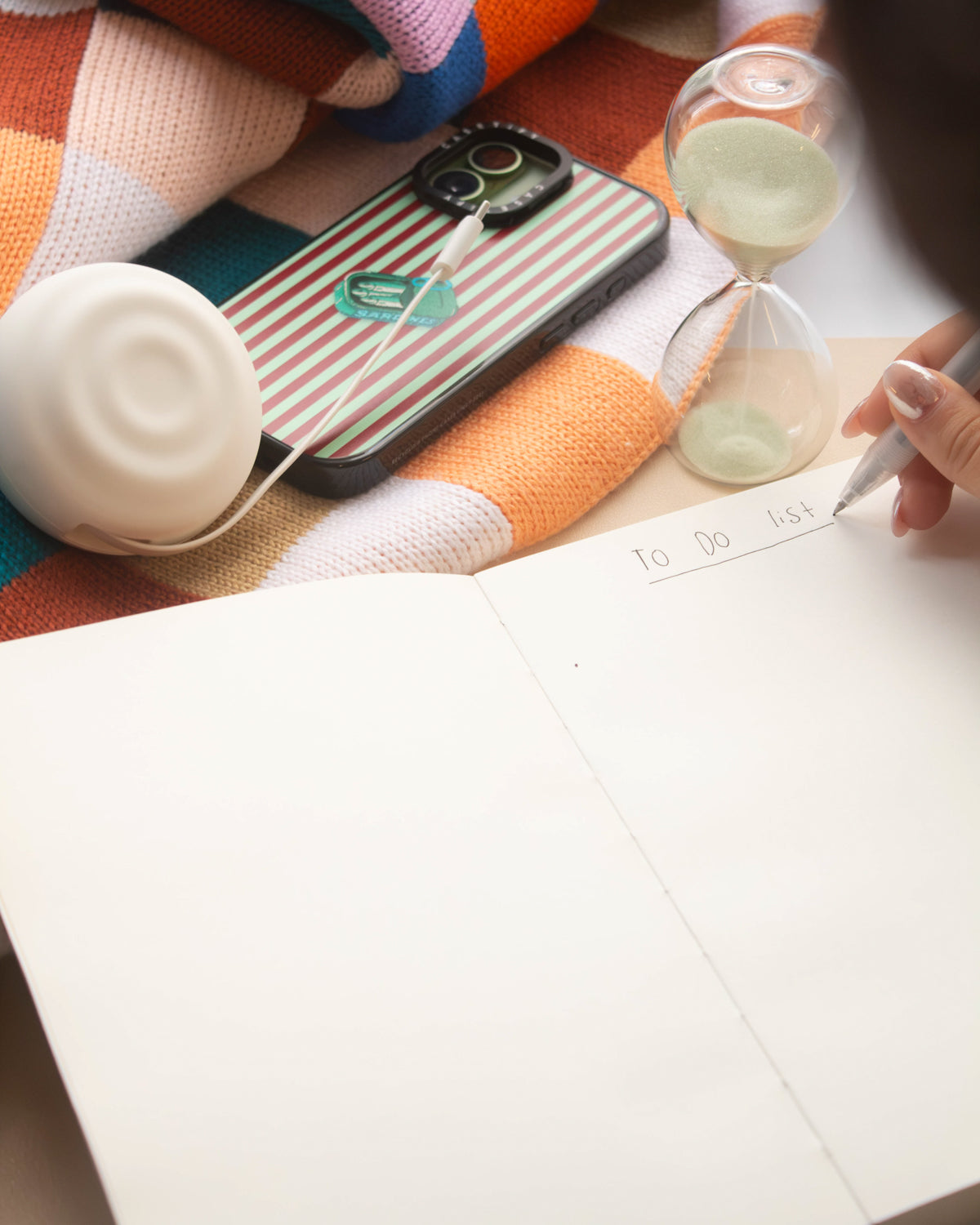 Poète notebook lying fully flat while someone writes next to a sand timer
