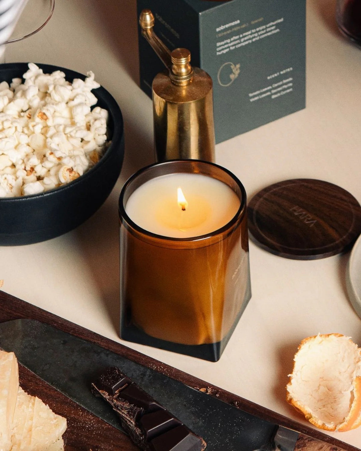 Luxury candle in a glass container on a table with popcorn and snacks