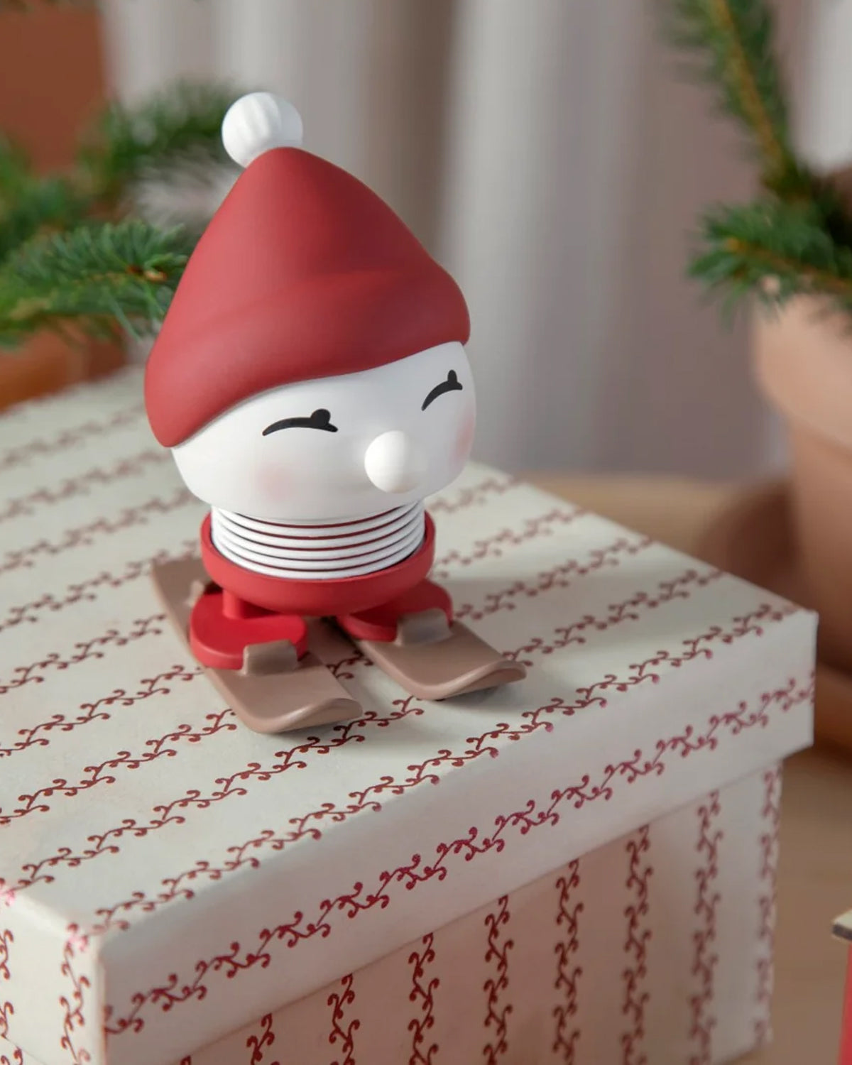 Red-capped Hoptimist Skiing Bimble standing on a wrapped gift box