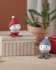 Red and blue Hoptimist skiing figures among wrapped gift boxes and a potted fir