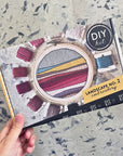Hand holding the Kate Wyatt Landscape No. 2 embroidery kit box