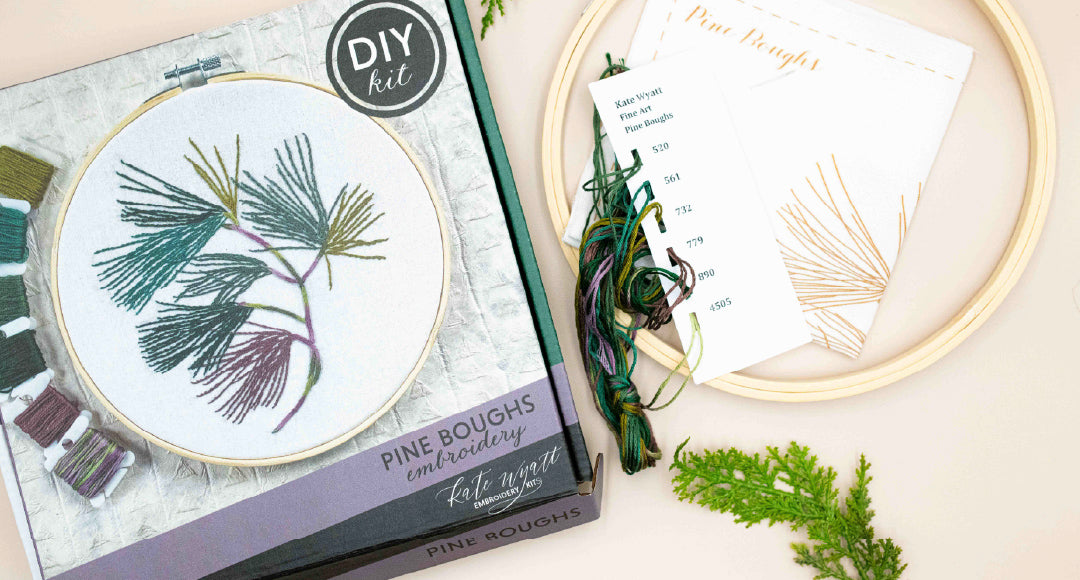 Pine Boughs embroidery kit with its finished hoop, instructions and greenery