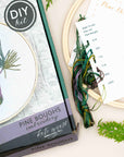 Pine Boughs embroidery kit with its finished hoop, instructions and greenery