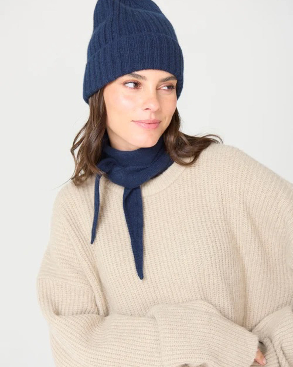 Model in a navy beanie and cream sweater wearing the navy Laolao cashmere mini scarf