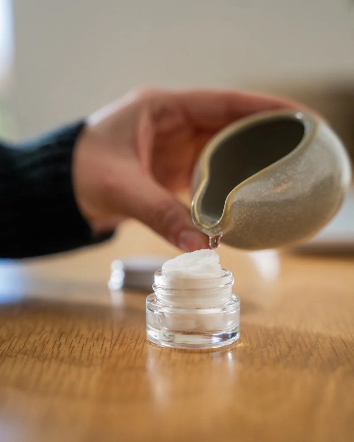 Hand pouring water from a ceramic dish onto the 'Rest Your Eyes' aromatherapy eye towel