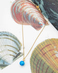 Necklace with a turquoise stone bead pendant on a background of seashells