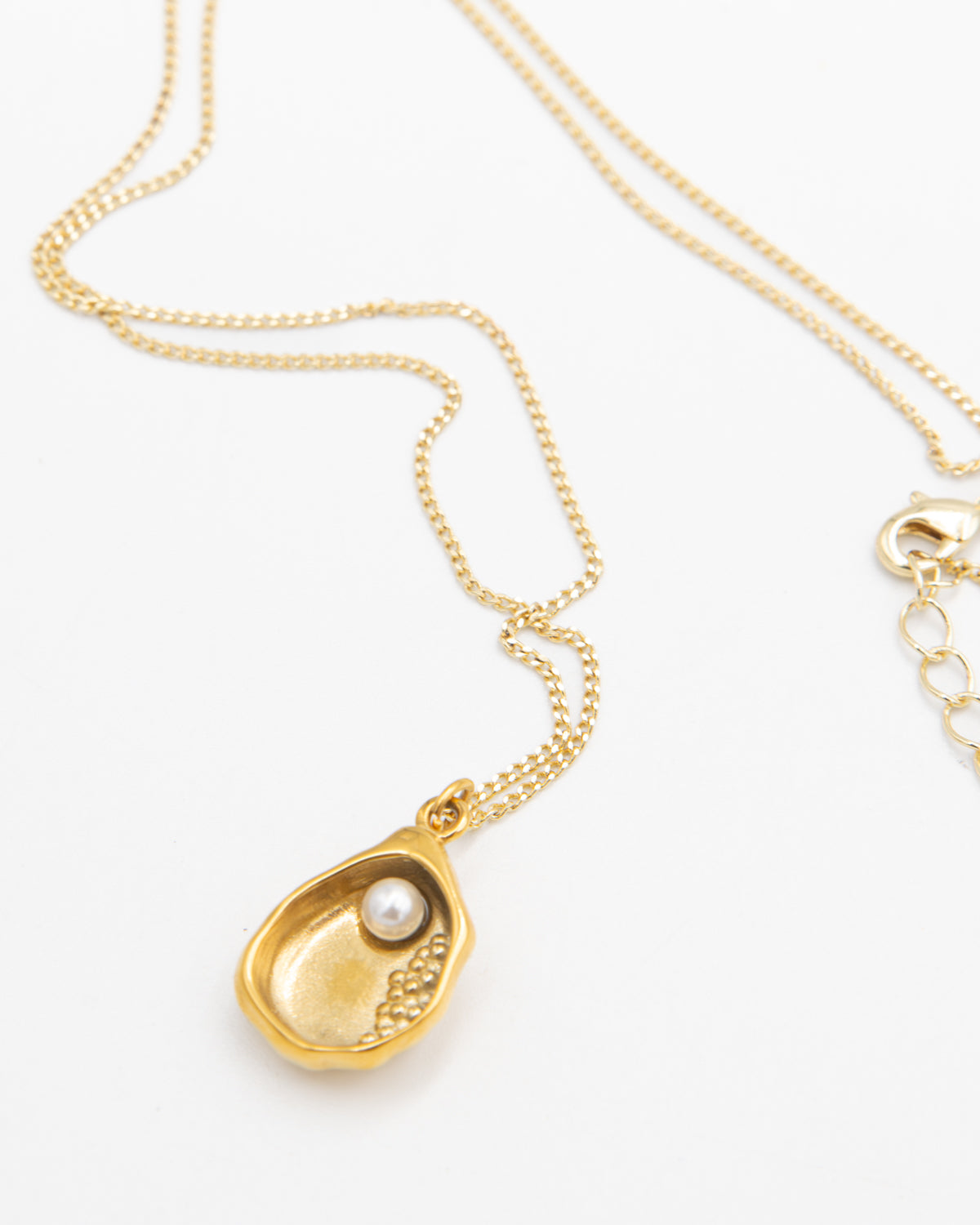 Gold necklace with a shell-shaped pendant with a glass pearl on a white background