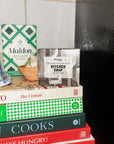 Stack of books with a Maldon sea salt flakes box and Mayron's Goods soap bar on top 
