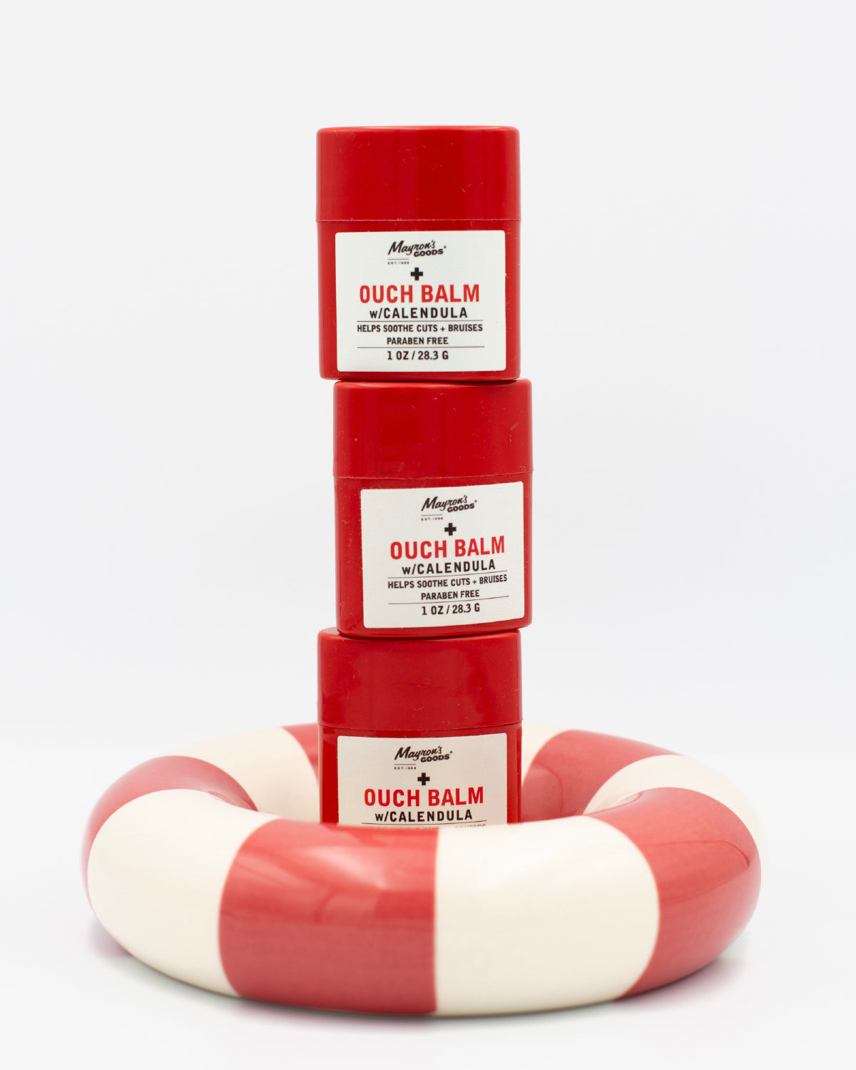 Stack of 3 red and white 'Ouch Balm' stick containers on a white background 