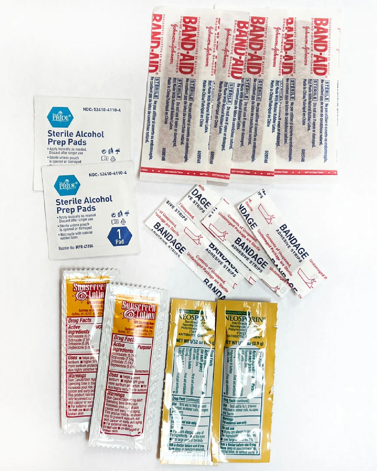 Pocket Aid Kit contents laid out: bandages, alcohol prep pads, ointment and sunscreen packs