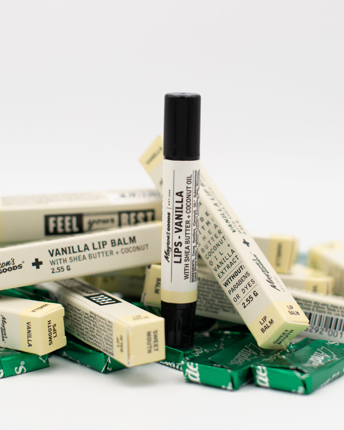 Single Mayron&#39;s Goods Vanilla Lip Balm tube and 9 packages on top of Andes candies green foil-wrapped mints