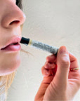 Close up of woman applying Mayron's Goods Vanilla Lip Balm to lips.