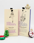 Two packages of 'miss maude's' dark chocolate: Theater Bar and Whiskey Business, with mini holiday ornaments around them on a white background.