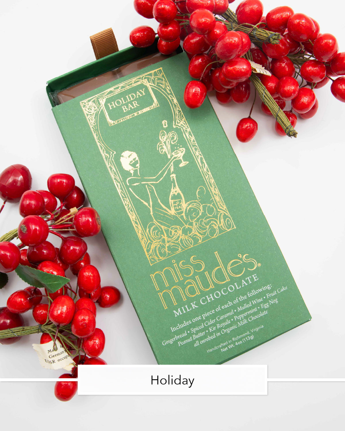 Miss Maude's Holiday milk chocolate bar in a green wrapper beside red berries
