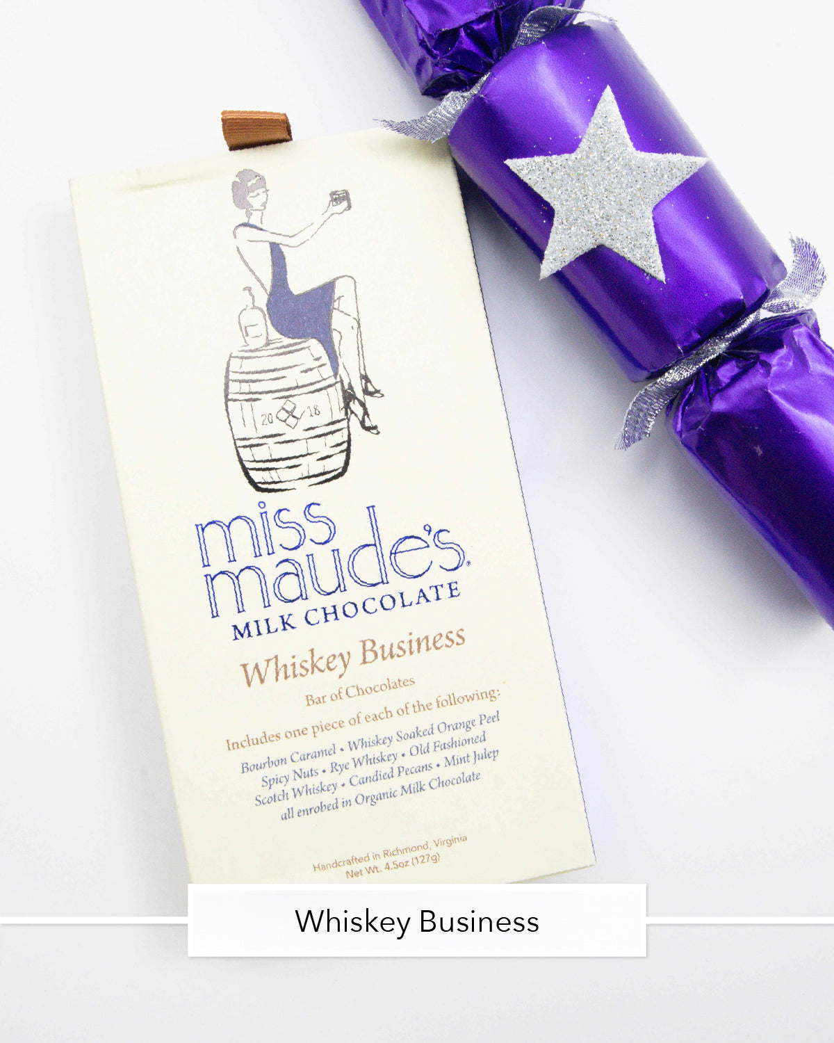 Miss Maude's Whiskey Business milk chocolate bar next to a purple party cracker