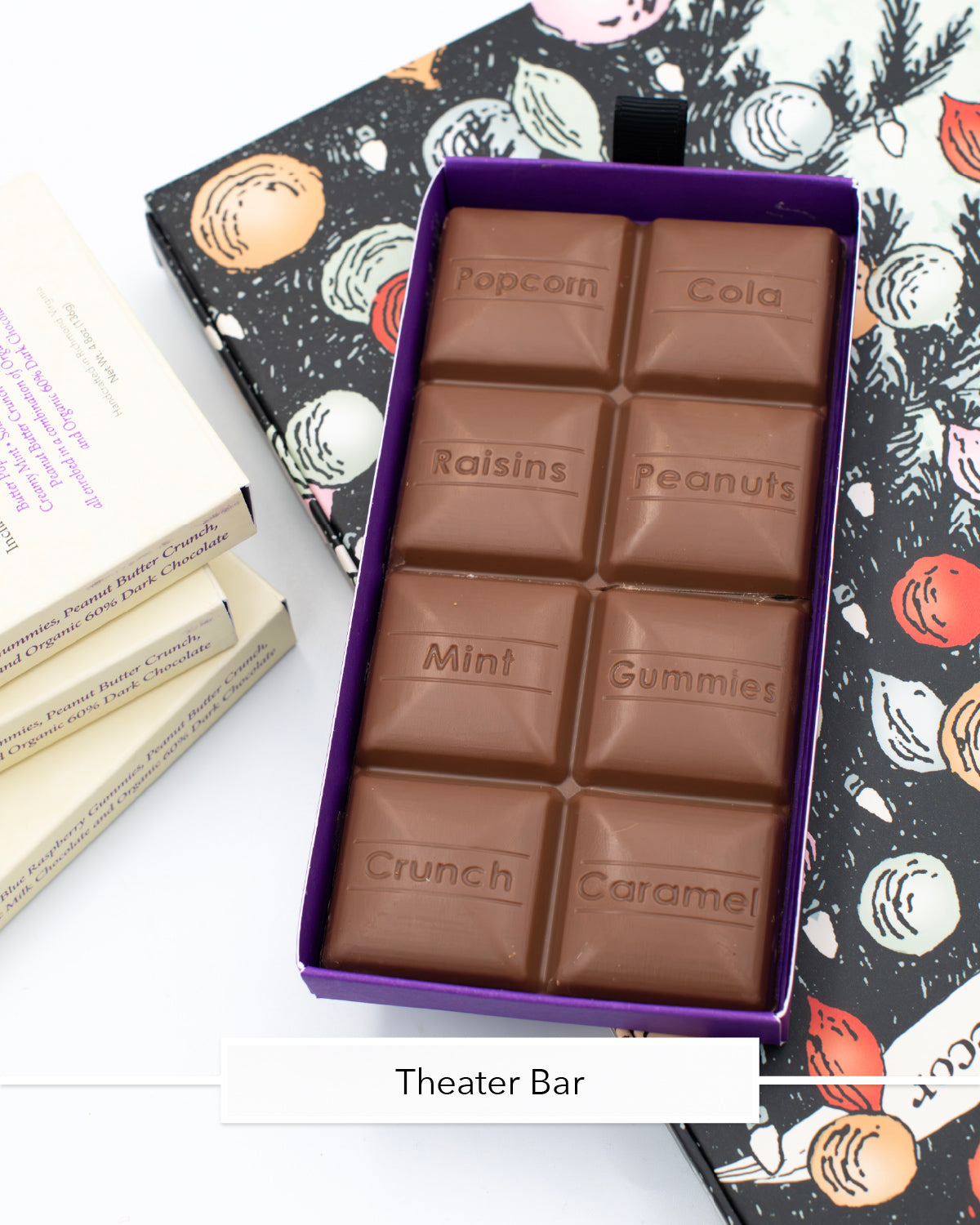 Open Miss Maude's Theater Bar showing milk chocolate squares stamped with flavors like popcorn and mint