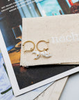 Daydreamer mini hoop earrings with porcelain cloud and moon charms on a Nach canvas pouch