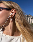 Woman with earbuds wearing a Daydreamer gold hoop with a white crescent moon charm outdoors