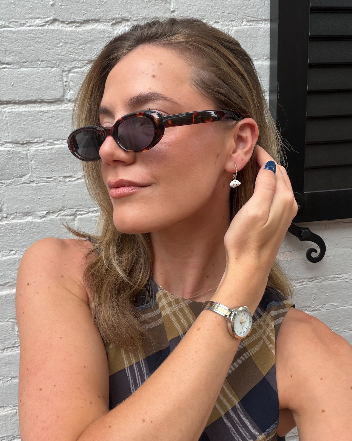 Woman in sunglasses and a plaid top wearing a Daydreamer mini hoop with a cloud charm