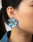 Close-up of an ear wearing the Frost Flower earring in blue and aqua with a gold center
