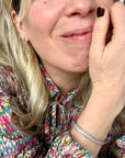 Close-up of a woman wearing a floral dress and mini gold hoop bee earrings