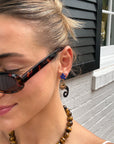 Woman in tortoiseshell sunglasses wearing the blue flower and gold sun drop earring
