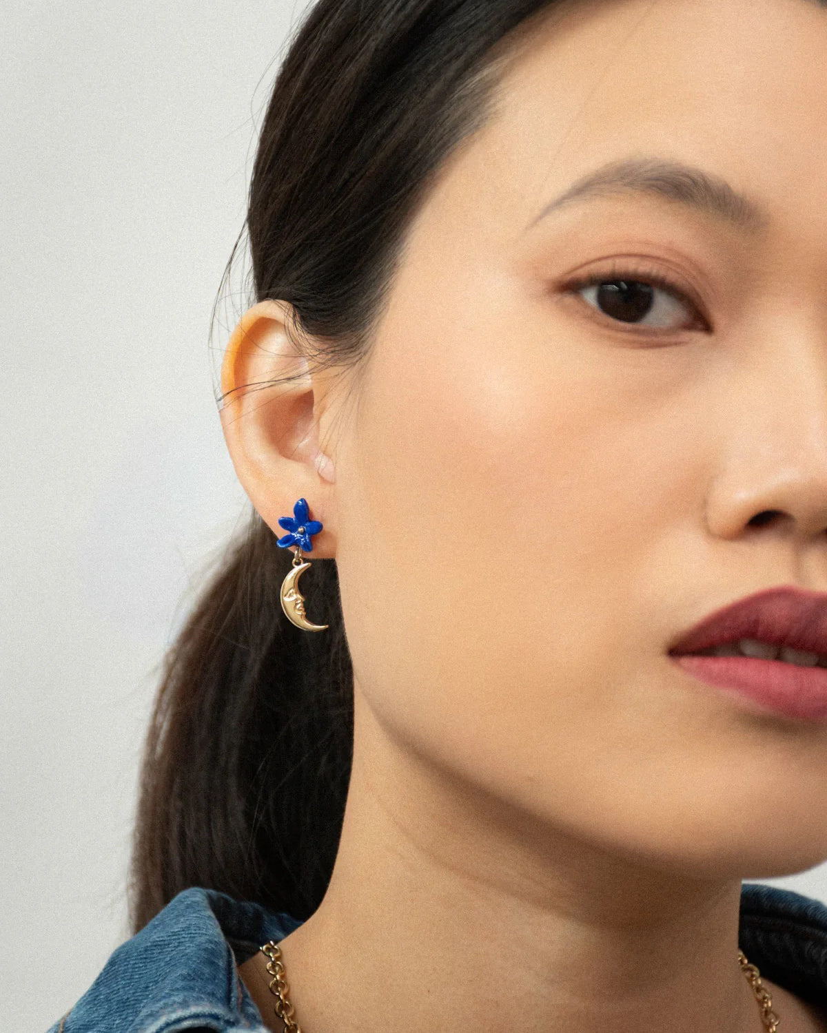 Woman wearing the Once in a Blue Moon earring with a blue flower stud and gold crescent moon