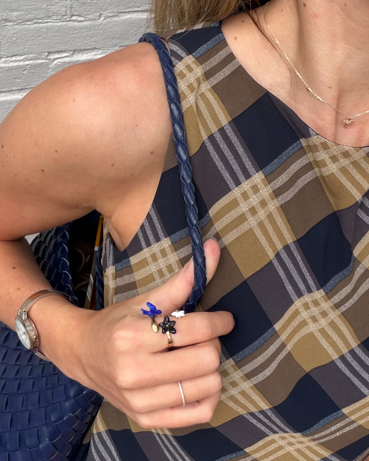 Close-up of a hand on a navy woven bag strap wearing the blue bird Once Upon a Time ring