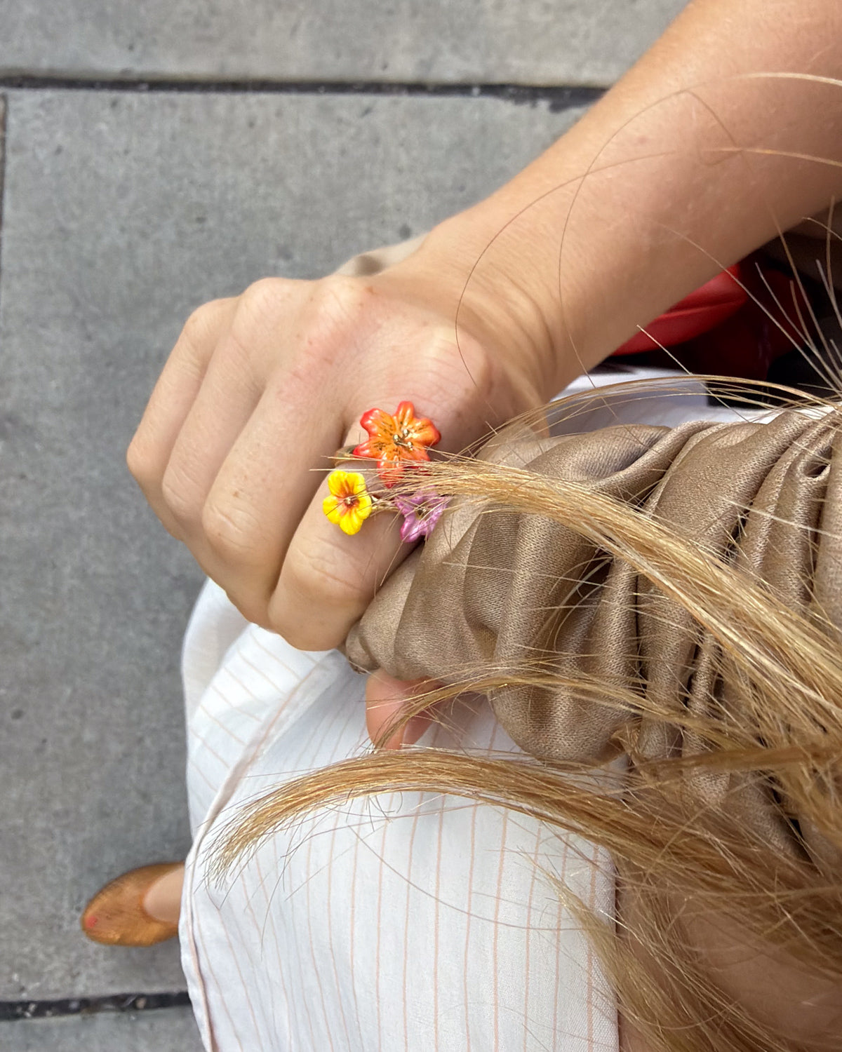 A hand-painted porcelain floral and gold ring worn on a person's hand