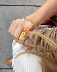 A hand-painted porcelain floral and gold ring worn on a person's hand